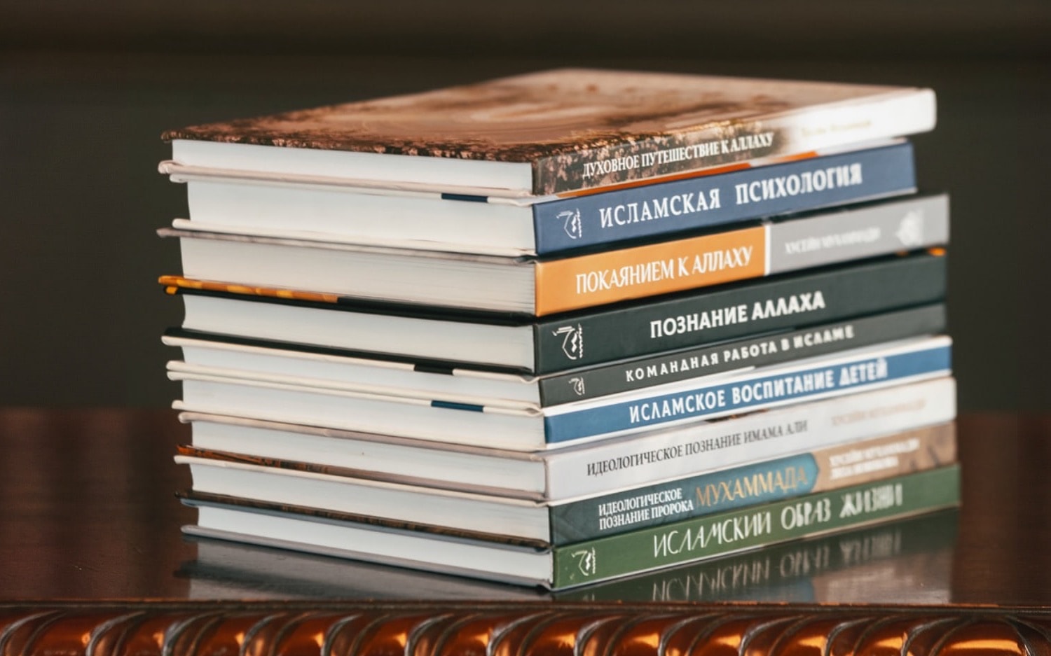 Стопка десяти изданных книг школы «Маариф» на столе у стеллажа